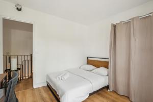 een slaapkamer met een bed met witte lakens en kussens bij Duplex apartment downtown with parking in Cergy