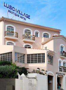 a large pink building with a sign on it at Luso Village Boutique Hotel in Luso