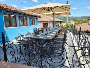 una mesa larga con sillas y una sombrilla en el patio en OldHouse, en Koprivshtitsa