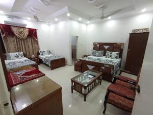 uma sala de estar com 2 camas, uma mesa e uma cadeira em Hotel Royal Residency em Karachi