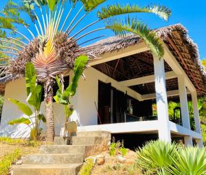 une maison avec un palmier en face dans l'établissement Hotel Océan Beach Sakatia, à Nosy Be