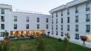 duży biały hotel z trawnikiem przed nim w obiekcie Holiday Hotel w Tiranie