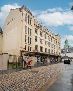 um edifício numa rua com pessoas a andar na frente dele em Budgetel- Kong Oscarsgate 22 em Bergen