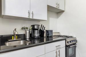 - une cuisine blanche avec évier et cuisinière dans l'établissement Hidden Cozy 2BD apartment In Manhattan, à New York