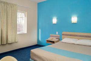 a blue room with a bed and a window at Motel 6-Peterborough, ON in Peterborough