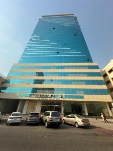 a tall blue building with cars parked in front of it at فندق الخلفاء الماسي in Makkah