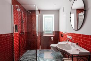 un bagno rosso con lavandino e specchio di Magazin Rooms a Salisburgo