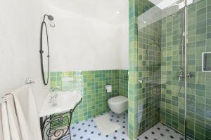 un bagno piastrellato verde con servizi igienici e lavandino di Magazin Rooms a Salisburgo