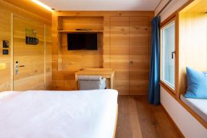 een kleine slaapkamer met een bed en een televisie bij chetzeron in Crans-Montana