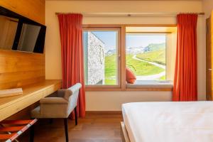 een slaapkamer met een raam met rode gordijnen bij chetzeron in Crans-Montana