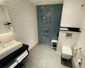 e bagno con doccia, servizi igienici e lavandino. di Holiday Inn Dijon Sud - Longvic, an IHG Hotel a Digione