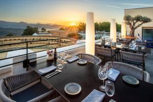 een restaurant met tafels en stoelen op een balkon met uitzicht op de zonsondergang bij Catalonia Ronda in Ronda