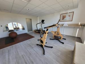 um ginásio com duas bicicletas de exercício num quarto em The Originals Boutique Hôtel Amiens Sud em Amiens