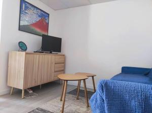 a living room with a bed and a table and a tv at Le Dragon - Appartement centre, Piscine partagée, Wifi, Jardin, Gare à 500m in Niort