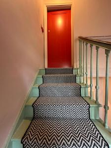 escalera con puerta roja y alfombra blanca y negra en Westways House, en Cobh