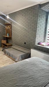 a bedroom with two beds and a brick wall at Luxury Live in Kamianets-Podilskyi