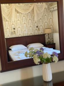 un espejo que refleje una cama con flores en un jarrón en Hotel Hera, en Skala Potamias