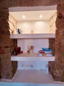 Loft Porto Romano Olbia Centro في أولبيا: رف في جدار مع كتب عليه