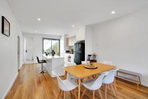 a kitchen and dining room with a wooden table and white chairs at Cozy Townhouse in Werribee centre in Werribee