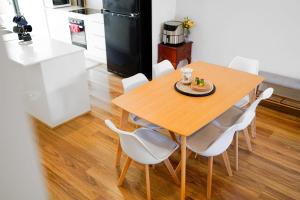 a kitchen with a wooden table and white chairs at Cozy Townhouse in Werribee centre in Werribee