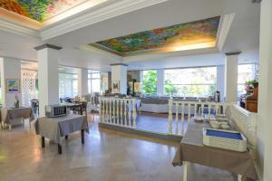 a restaurant with tables and chairs and a ceiling with a painting at Hotel du Lac in Talloires