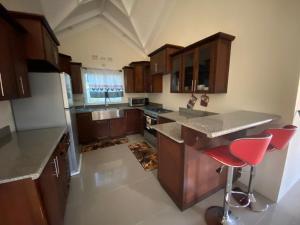 cocina grande con armarios de madera y taburetes rojos en Royal Palm Luxury Villas, en Ocho Ríos