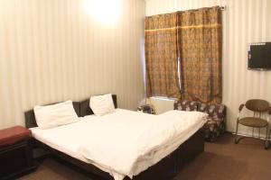 a bedroom with a bed and a chair in it at Malika Kohsar Hotel Murree in Murree