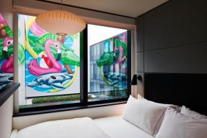 een slaapkamer met een bed en 2 ramen met flamingo's bij citizenM Miami South Beach in Miami Beach