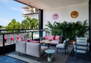 een kamer met een balkon met stoelen en tafels bij citizenM Miami South Beach in Miami Beach