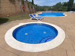 una piscina con due sedie e due piscine di Apartamento Loft, LLoret de Mar a Lloret de Mar