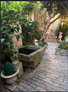 une fontaine en pierre dans un jardin avec quelques plantes dans l'établissement Villa Romana, à Saint-Tropez