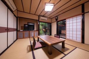 um quarto com uma mesa de madeira e cadeiras em Bessou Konjakuan em Yufu