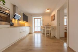 una cocina con armarios blancos y una mesa con sillas. en Residence Tamperhof, en San Candido