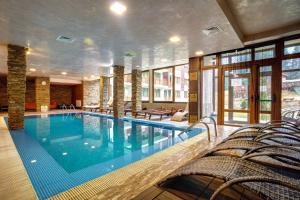 una gran piscina con sillas en una habitación de hotel en Sunrise Apartment Pamporovo, en Pamporovo