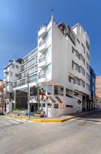 un edificio blanco en una calle al lado de un aparcamiento en Conde de Lemos Hotel, en Puno