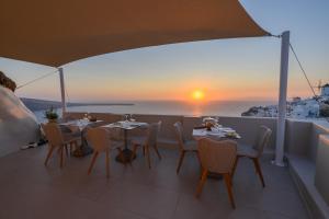 d'une table et de chaises sur un balcon avec vue sur le coucher du soleil. dans l'établissement Art Maisons Oia Castle, à Oia