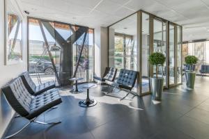 een lobby met 2 stoelen en glazen ramen bij Lagrange Aparthotel Lyon Lumière in Lyon