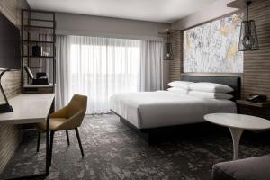 Cette chambre comprend un lit, un bureau et une table. dans l'établissement Marriott Indianapolis North, à Indianapolis