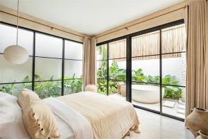 - une chambre avec un grand lit et une grande fenêtre dans l'établissement Alma Bingin Boutique Hotel, à Uluwatu