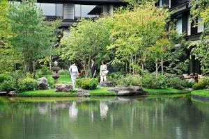 un groupe de personnes se promenant autour d'un étang dans un jardin dans l'établissement HOTEL THE MITSUI KYOTO, a Luxury Collection Hotel & Spa, à Kyoto