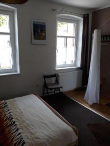 a bedroom with a bed and two windows and a chair at Allsaitig Klang- und Seminarzentrum Selb in Selb