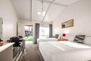 ein Hotelzimmer mit 2 Betten, einem Schreibtisch und einem Tisch in der Unterkunft Quality Hotel Lakeside in Bendigo