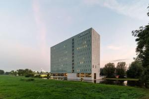 um edifício alto com um campo verde em frente em Radisson Hotel & Suites Amsterdam South em Amstelveen