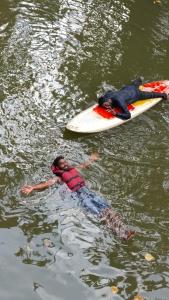 dos personas flotando en una tabla de surf en el agua en Horanadu Haranamakki Homestay, en Kalasa