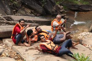 un grupo de hombres con chalecos salvavidas sentados junto a un río en Horanadu Haranamakki Homestay, en Kalasa