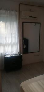 um quarto com um espelho e uma mala em frente a uma janela em Sindi Apartman em Bačka Palanka