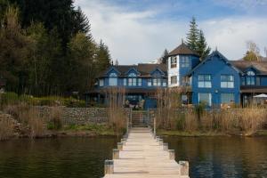 une maison bleue avec un quai en face de l'eau dans l'établissement Las Balsas Relais & Chateaux, à Villa La Angostura