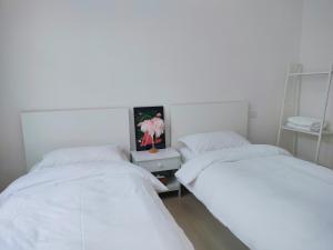 twee bedden in een kamer met witte muren bij Lotus Art Inn PEK Airport 菡庭筱院民宿北京首都机场店 in Shunyi