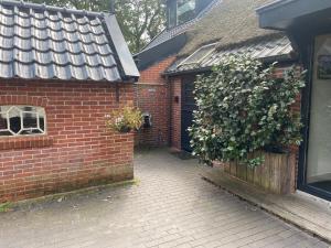 una casa de ladrillo con una puerta y un arbusto en Kindvriendelijk appartement de Hooge Stukken onder de rook van Groningen, en Eelde-Paterswolde