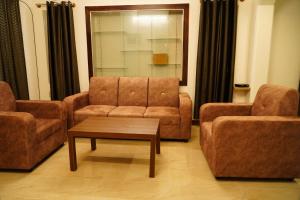 een woonkamer met 2 stoelen, een bank en een tafel bij Meridian Rooms and Service Apartment in Mysore